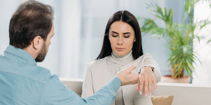 Hypnose Cham | sitzende Frau, ihre Hand wird vom Therapeuten gehalten