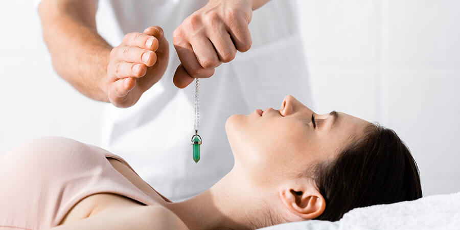 Hypnose Reinach | Edelstein wird über Hals von Frau gehalten