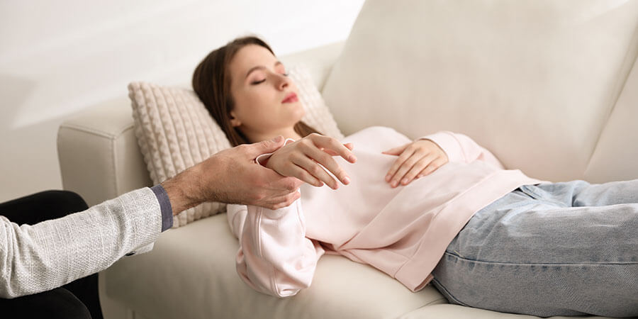 Hypnose Luzern | Frau liegt auf Couch, ihre Hand wird vom Therapeuten gehalten