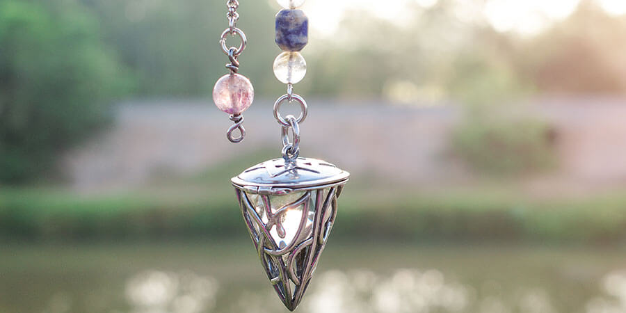 Hypnose Zürich | Pendel mit Kristallen, Teich im Hintergrund