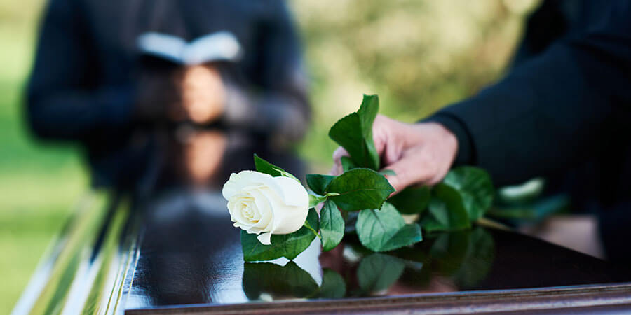 Bestattungen in Luzern | Trauerrede, auf Sarg wird weiße Rose gelegt