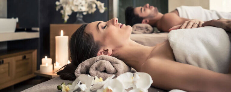 Body & Soul Figurstudio Seetal | Mann und Frau liegen im Wellness-Studio umgeben von Orchideen-Blüten