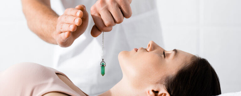 Hypnose Frauenfeld | Edelstein wird über Hals von Frau gehalten