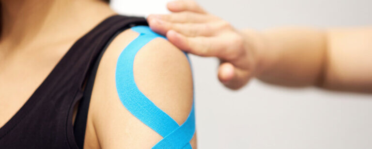 Kinesiologie Oerlikon | Schulter wird mit blauem Tape beklebt