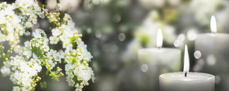 Bestattungen Baden | Blumenschmuck mit kleinen weißen Blüten und mehrere Kerzen