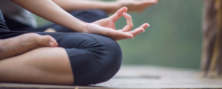 Yoga in Baden | Frauenbeine im Schneidersitz und Yogafingerhaltung Daumen und Zeigefinger berühren sich