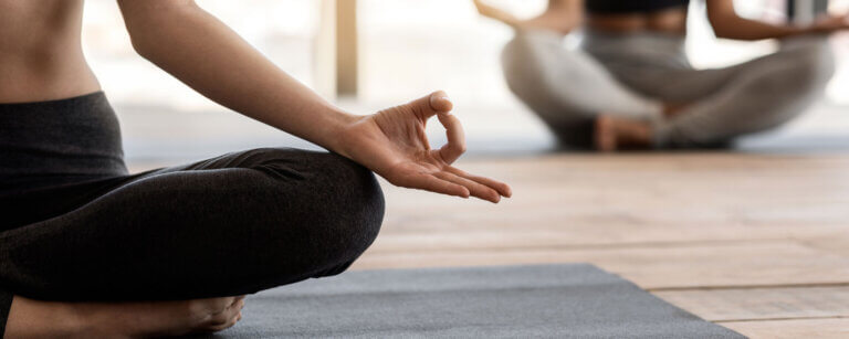 Yoga in Oerlikon | Frauenbeine im Schneidersitz und Yogafingerhaltung Daumen und Zeigefinger berühren sich