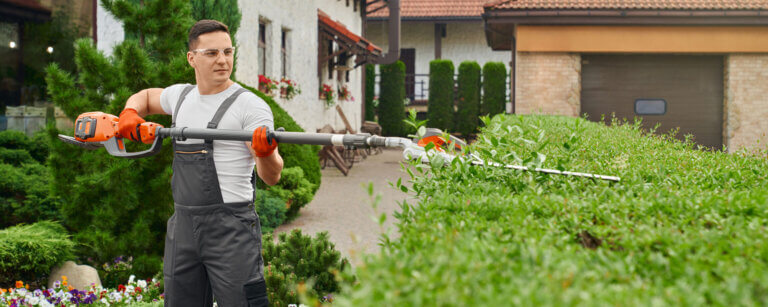 Hauswartung in Basel-Landschaft | Mann schneidet mit Akkuheckenschere eine Hecke