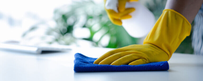 Hauswartung in Sursee | jemand reinigt eine Oberfläche mit Lappen und Spray in gelben Gummihandschuhen