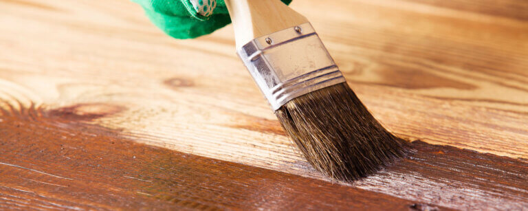 Hauswartung in Luzern | Hand streicht mit Pinsel Holz