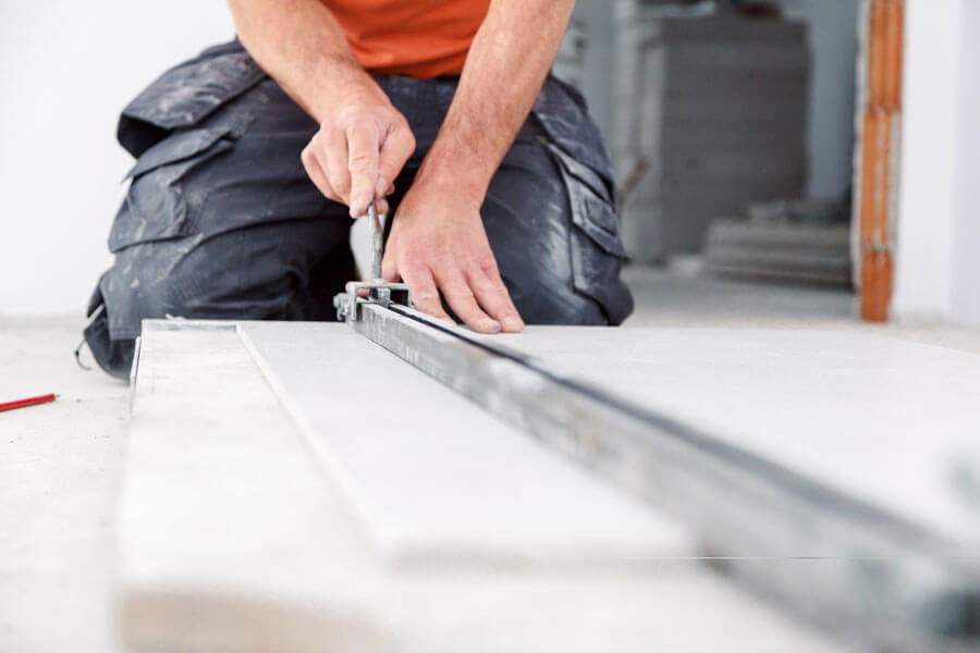 Umbau und Renovationen in Reinach | Fliesenleger schneidet Fliese mit Schneidtischwerkzeug