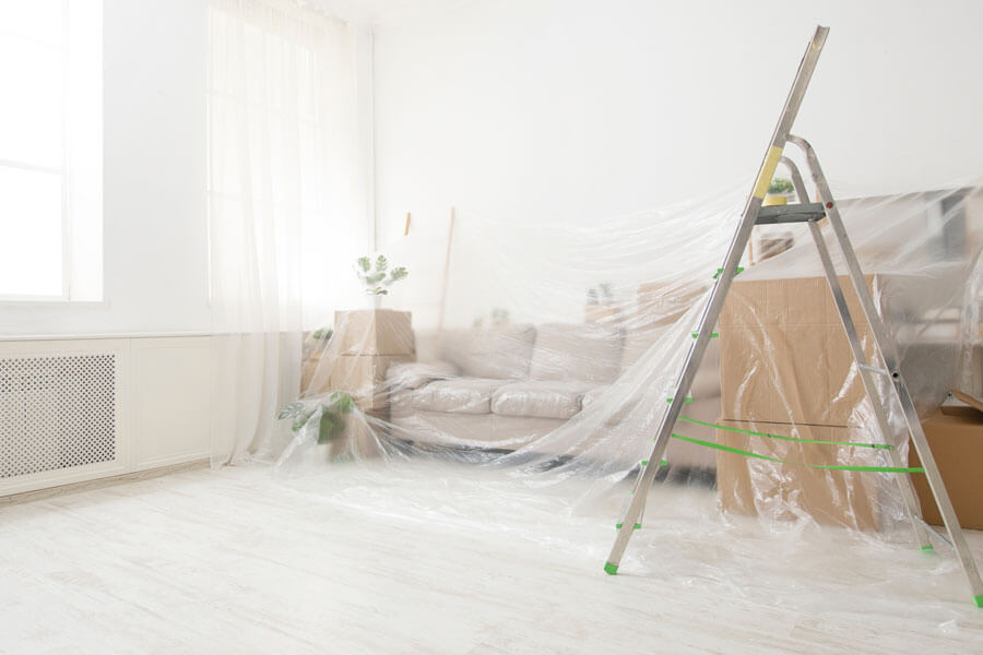 Umbau und Renovationen in Solothurn | Sofa und Kisten mit Folie abgedeckt zur Wohnzimmerrenovierung, Leiter steht im Vordergrund