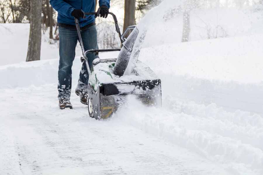 Hauswartung in Baden | Person arbeitet mit Schneefräse auf dem  Gehweg 