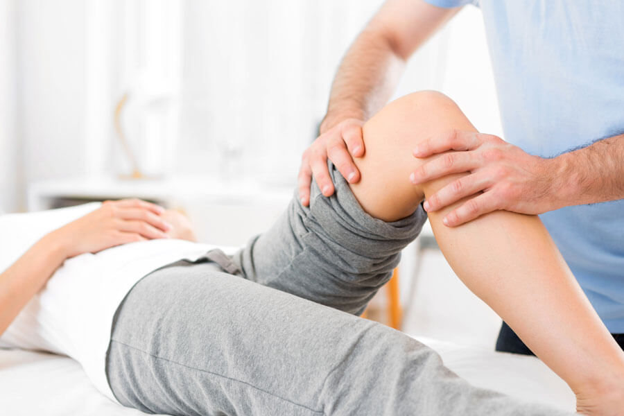 Physiotherapie in Aarau | Patientin wird vom Physiotherapeuten am Knie behandelt
