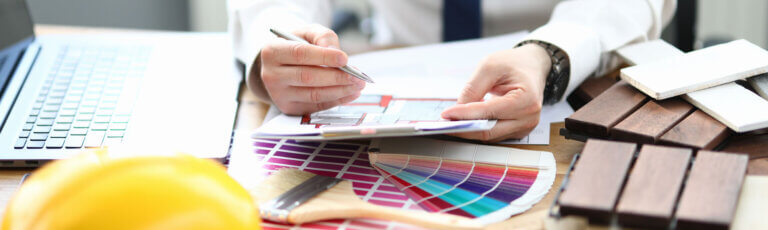 Umbau und Renovationen in Frauenfeld | erson plant am Tisch mit Laptop, Farbpalette und Mustern ein Projekt für eine Inneneinrichtung